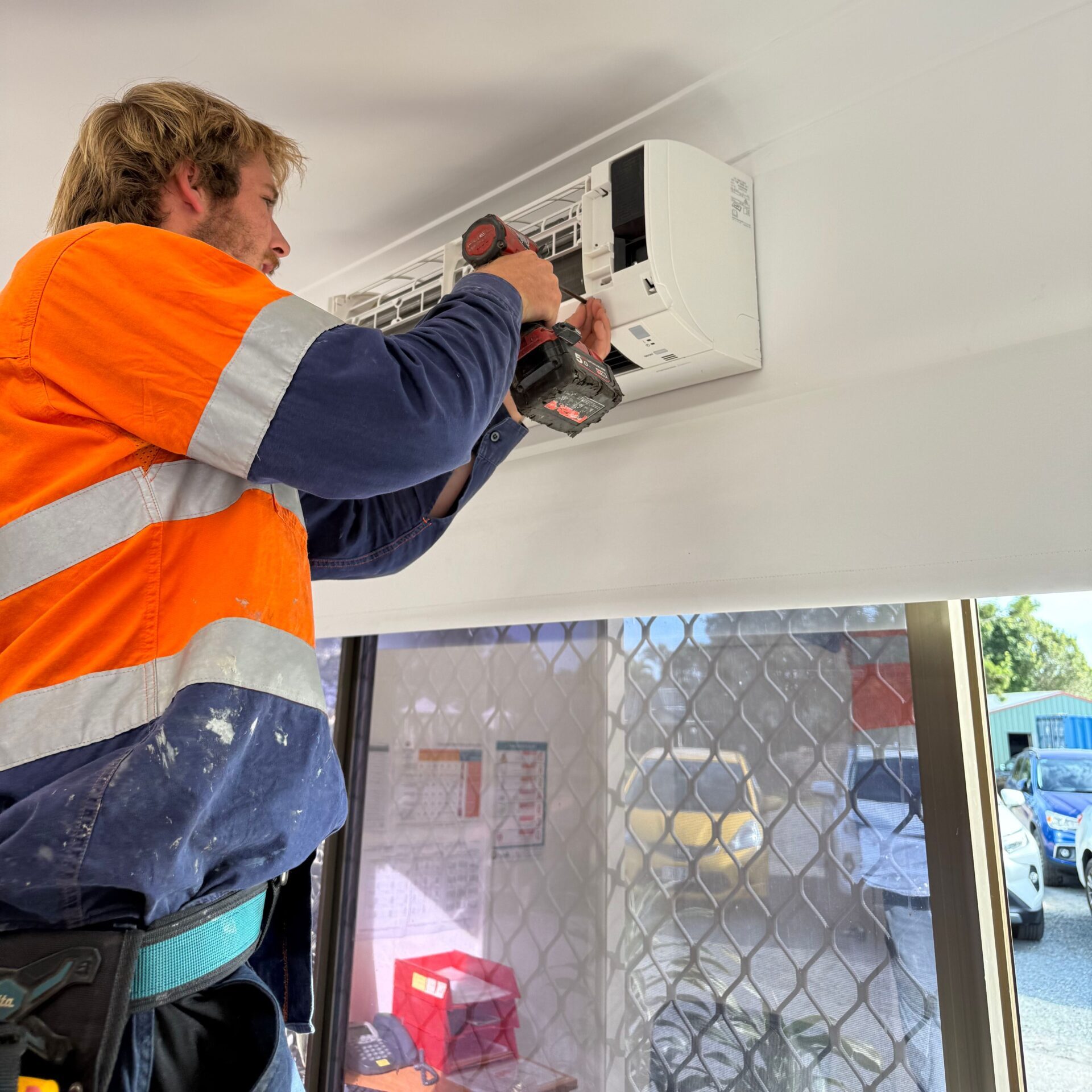 a licensed electrician from AIS electrical is doing an air conditioning cleaning for air conditioning maintenance